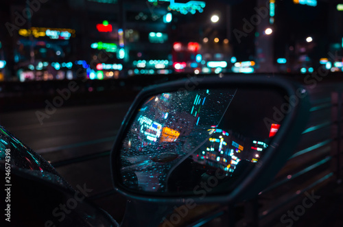 Raindrops on wet car mirror at night