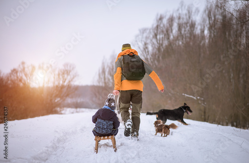 Canvas Print Young man and his son sledding in the winter park