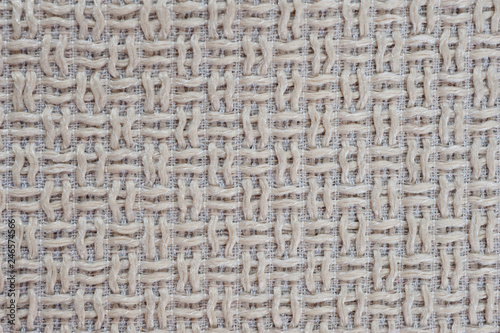 Textured fabric mat with woven wool beige yarn closeup shot..