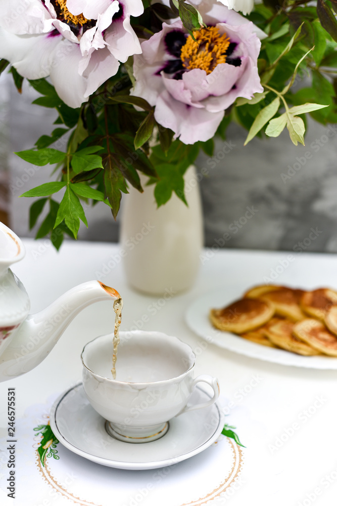 tea and pancakes on the background of beautiful pions. tea and pancakes on the background of beautiful pions.