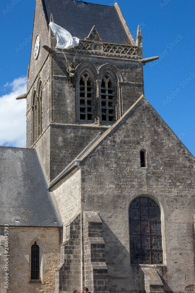 Historic church of Sainte mere l'eglise, with a paratrooper  hanging on the bell tower in Normady, France.