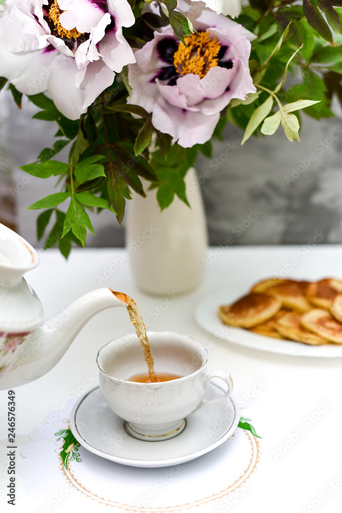 tea and pancakes on the background of beautiful pions. tea and pancakes on the background of beautiful pions.