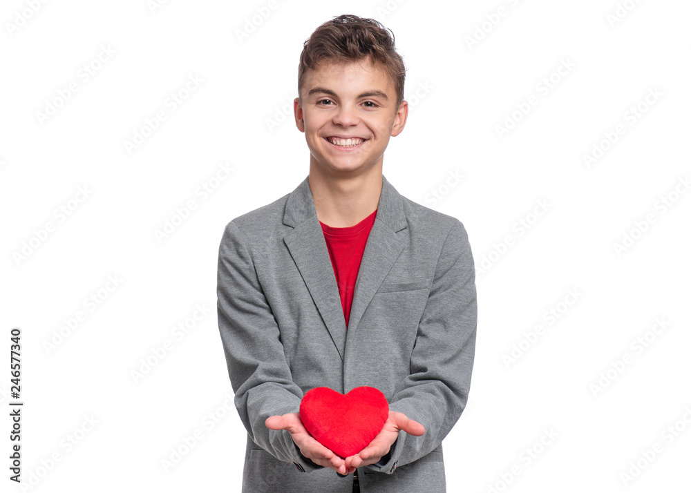 Happy Valentines Day. Cute young Teen Boy in Love with Red plush Heart in his hands. Smiling Child in grey suit, looking at camera, isolated on white background. Happy Valentines Day. Cute young Teen Boy in Love with Red plush Heart in his hands. Smiling Child in grey suit, looking at camera, isolated on white background.