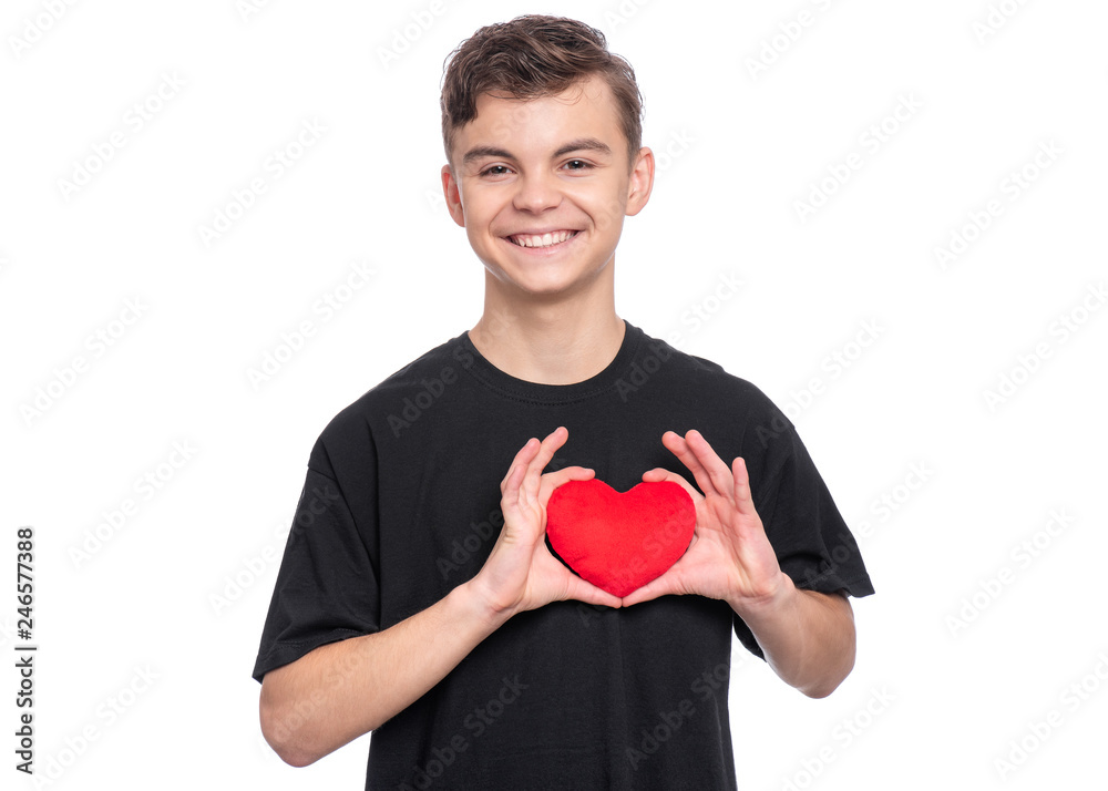 Happy Valentines Day. Cute young Teen Boy in Love with Red plush Heart in his hands. Smiling Child in black T-shirt, looking at camera, isolated on white background. Happy Valentines Day. Cute young Teen Boy in Love with Red plush Heart in his hands. Smiling Child in black T-shirt, looking at camera, isolated on white background.