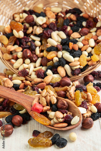dried fruits and nuts on a wooden white background with a wooden spoon