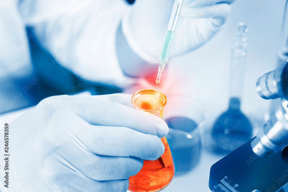 Hands of young Asian man and white microscope in science laboratory with red liquid and dropper for testing. Technician dripping red water on slide glass in science lab. Hands of young Asian man and white microscope in science laboratory with red liquid and dropper for testing. Technician dripping red water on slide glass in science lab.