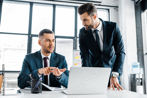 handsome businessman talking with coworker in modern office