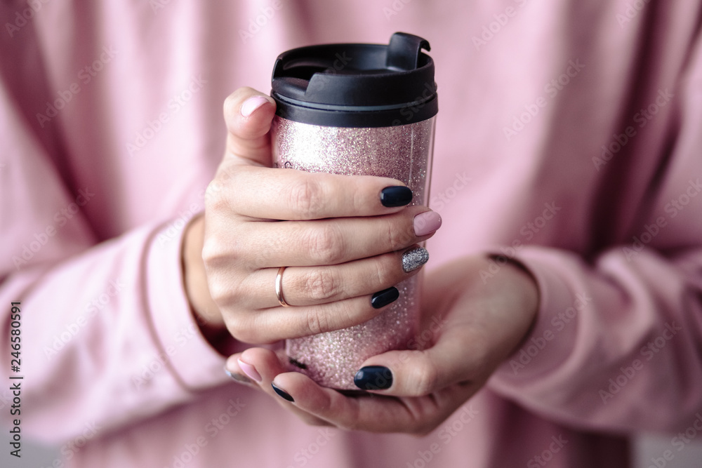 Gorgeous manicure, pastel tender pink color nail polish, closeup photo. Female hands hold a plastic coffee cup over simple background