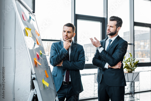 handsome businessmen looking at white board and talking in modern office