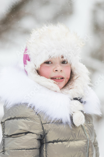 Beautiful little girl in warm jacket in winter forest