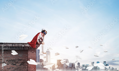 Girl power concept with cute kid guardian against cityscape background. Mixed media