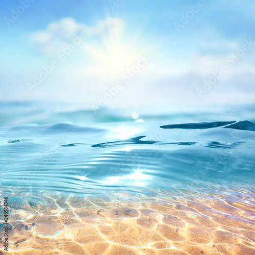 Summer landscape, nature of tropical with rays of sun light. Beautiful sun glare in wave of transparent blue water on beach against blue sky. Copy space, summer vacation concept.