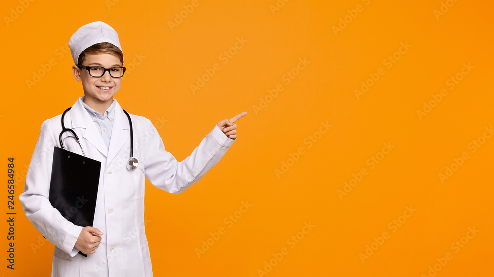 Cute smiling boy playing doctor on orange background Cute smiling boy playing doctor on orange background