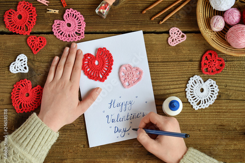 Making of handmade Valentine greeting card with crochet openwork hearts. Making of handmade decoration. Valentines Day crafts. Childrens DIY, hobby concept, gift with your own hands.