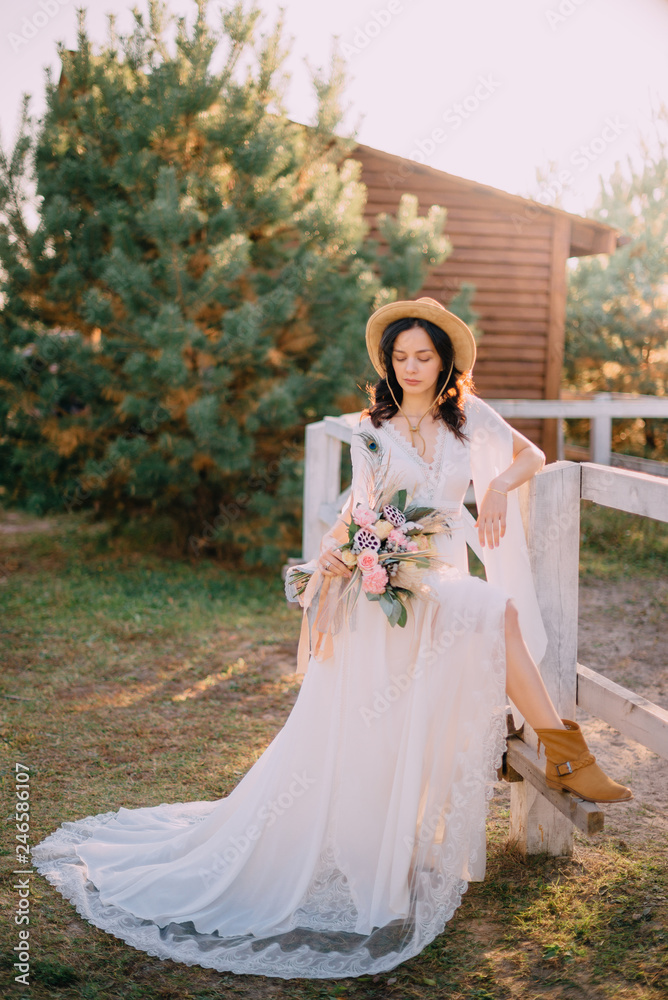 cowboy style bride stands near fence on ranch cowboy style bride stands near fence on ranch