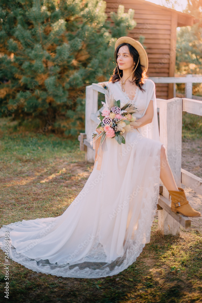 cowboy style bride stands near fence on ranch