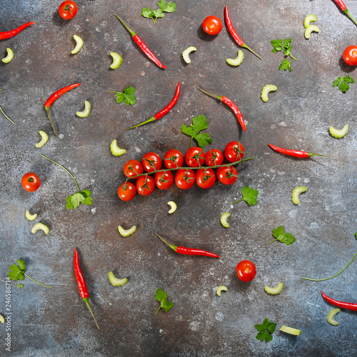 Pattern made of fresh vegetables and branch of cherry tomatoes on dark stone background. Flat lay, top view.