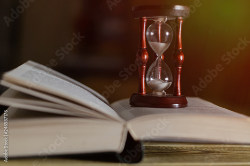 Hourglass on the book. The concept of time and reading.