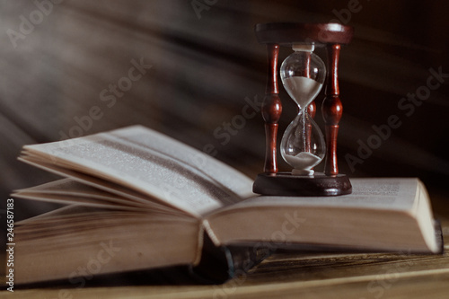 Hourglass on the book. The concept of time and reading.