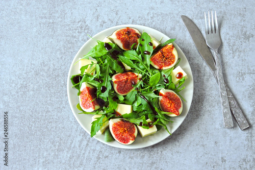 Fresh juicy salad with figs, arugula and white cheese. Healthy colorful fitness salad. Superfoods