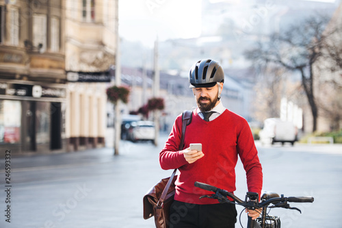 Hipster businessman commuter with bicycle and smartphone on the way to work in city.