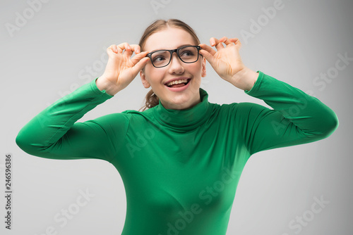 Smiling girl in glasses posing in studio  and looks sideaway happily. - Image