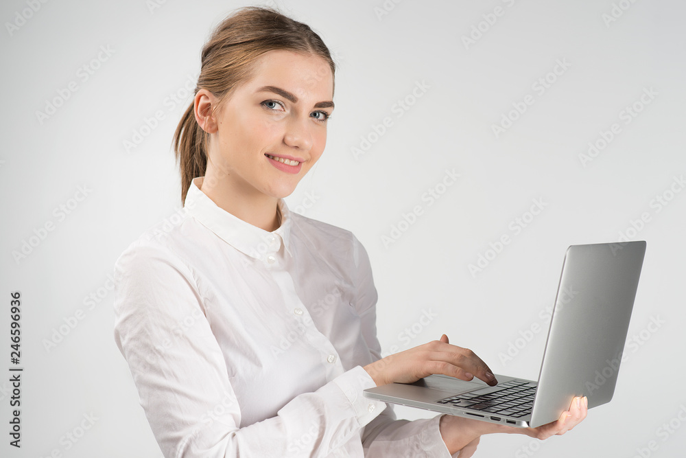 Smiling business woman in white shirt holding laptop and while standing and looking at the camera Smiling business woman in white shirt holding laptop and while standing and looking at the camera