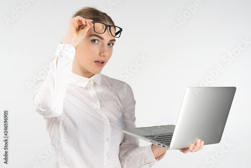 Amased business woman in glasses  holding laptop and raises up her glasses photo