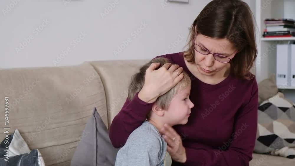 Cute little boy is coughing, sitting with his mother in a living room Cute little boy is coughing, sitting with his mother in a living room