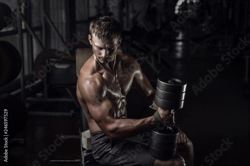 Fitness guy holding huge dumbbell in old rusty gym. Shallow depth of field © honored