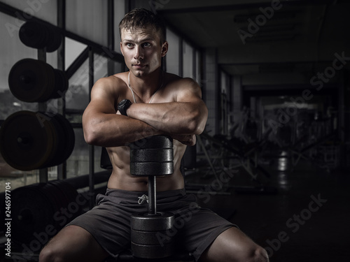 Fitness guy holding huge dumbbell in old rusty gym. Shallow depth of field © honored