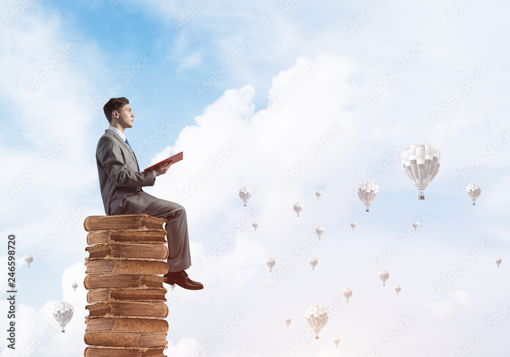 Man student reading book and aerostats flying around in air Man student reading book and aerostats flying around in air