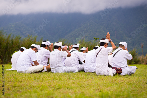 Men praying at Pura Bratan Temple on lake in Bali, Indonesia