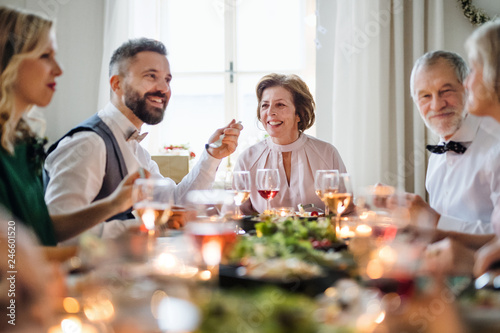 A big family sitting at a table on a indoor birthday party  eating.