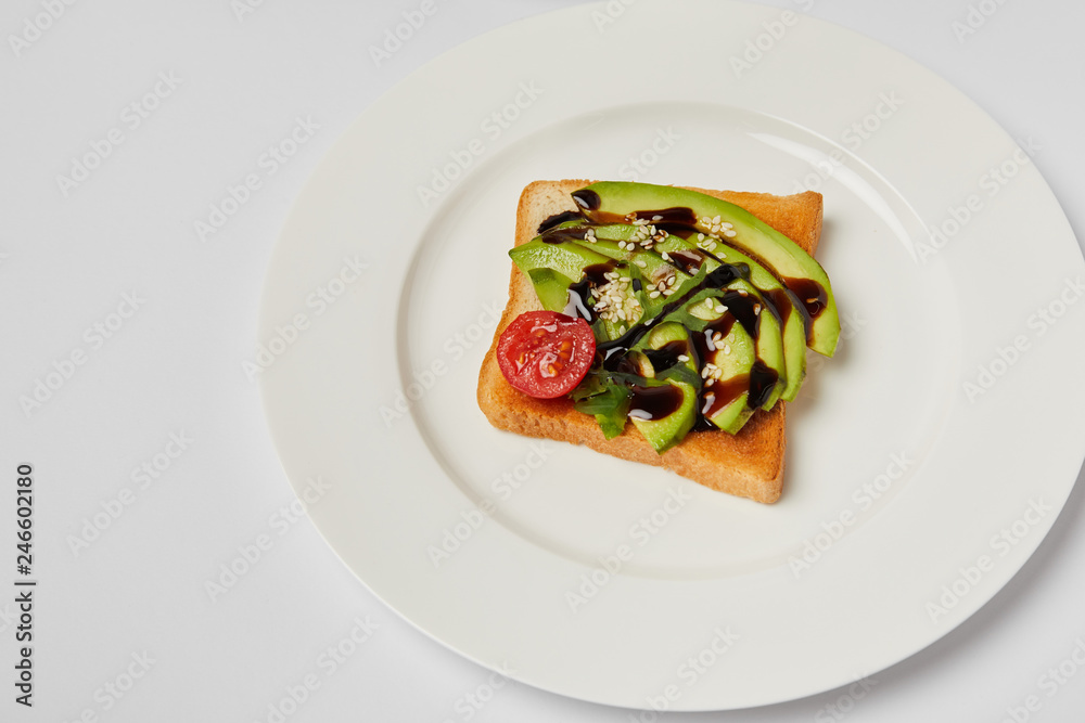 top view of toast with avocado and cherry tomato on grey backgroud