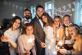 A young bride, groom and guests posing for a photograph on a wedding reception.