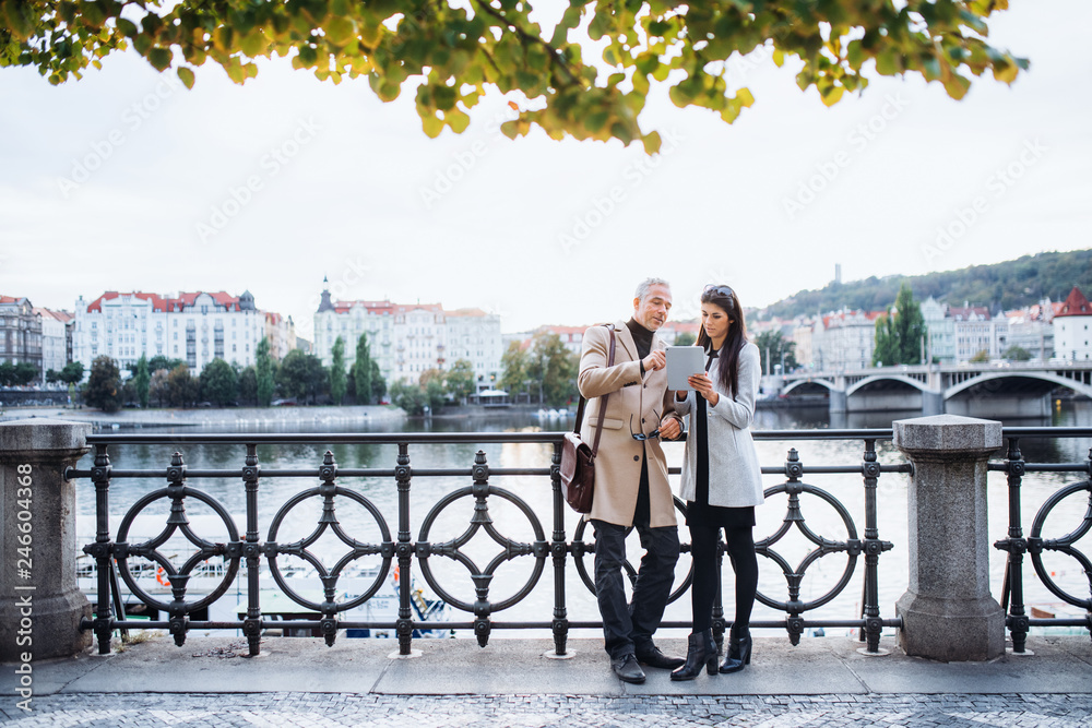 custom made wallpaper toronto digitalMan and woman business partners with tablet standing by a river in city of Prague.