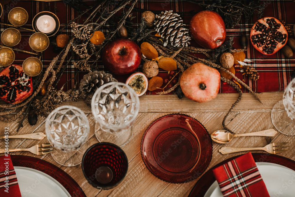 .Detail photograph of a table prepared and decorated for a party diner. Autumnal and festive decoration, with wood pineapples, candles, fruits and red colors. Lifestyle. Food photography .Detail photograph of a table prepared and decorated for a party diner. Autumnal and festive decoration, with wood pineapples, candles, fruits and red colors. Lifestyle. Food photography