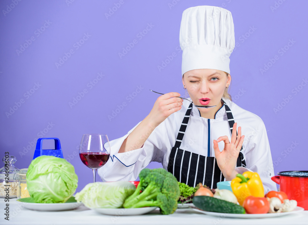 Girl in hat and apron. Cooking healthy food. Fresh vegetables ingredients for cooking meal. Professional cooking tips. Woman chef try taste food. Gourmet main dish recipes. Delicious recipe concept Girl in hat and apron. Cooking healthy food. Fresh vegetables ingredients for cooking meal. Professional cooking tips. Woman chef try taste food. Gourmet main dish recipes. Delicious recipe concept