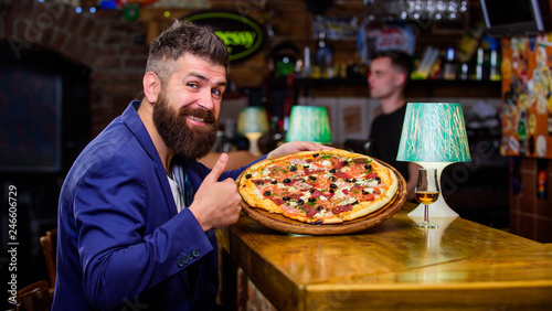 Hipster client sit at bar counter. Man received delicious pizza. Enjoy your meal. Cheat meal concept. Pizza favorite restaurant food. Fresh hot pizza for dinner. Hipster hungry eat italian pizza