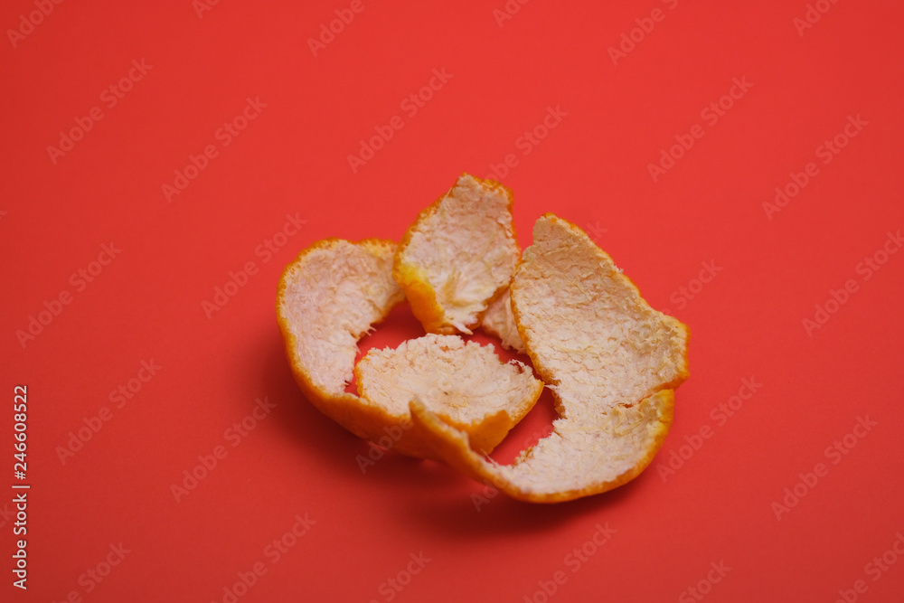 Peeled orange skin shot on a plain isolated red background. Peeled orange skin shot on a plain isolated red background.