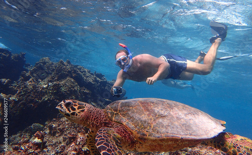 Young tourist making snorkelling with a turtle in Maldives islands