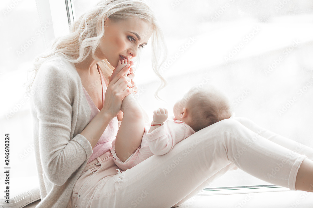 Young mother taking care of her little baby girl. Beautiful mom and her daughter indoors in the bedroom. Loving family. Attractive mum holding her child. Young mother taking care of her little baby girl. Beautiful mom and her daughter indoors in the bedroom. Loving family. Attractive mum holding her child.