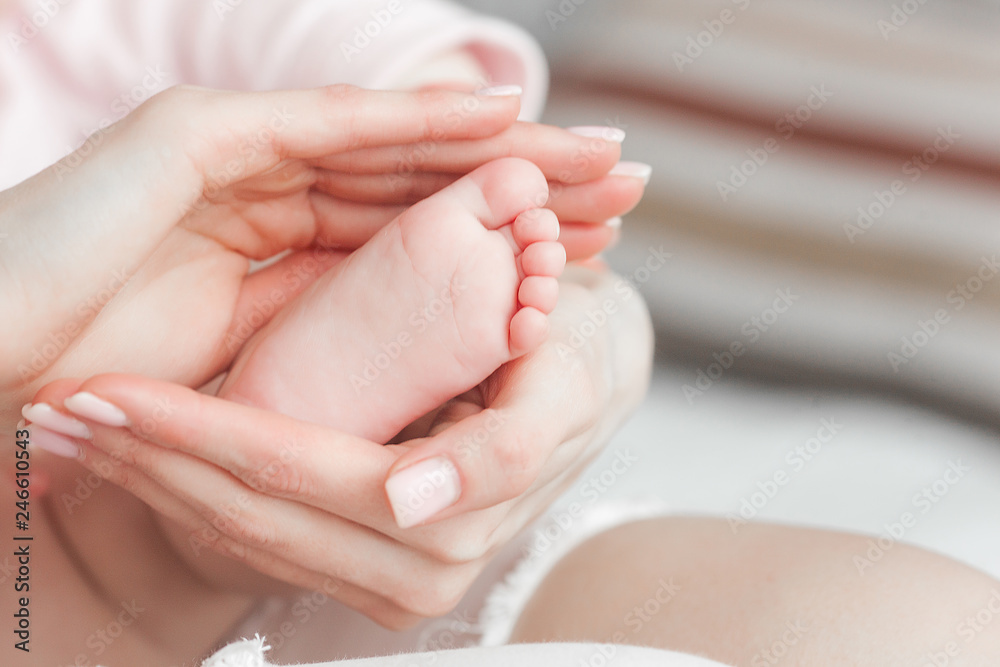 Baby`s feet closeup picture. Mother`s hands holding child`s foot. Little girl`s fingers at front. Background of parenthood. Baby`s feet closeup picture. Mother`s hands holding child`s foot. Little girl`s fingers at front. Background of parenthood.