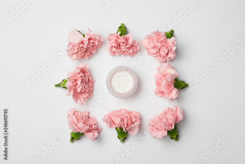 Flat lay of carnations flowers in square arranging and cream container on white background