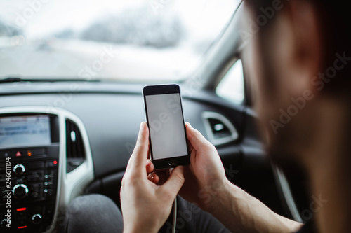 The man holds the phone in his hand.On the background of the car.