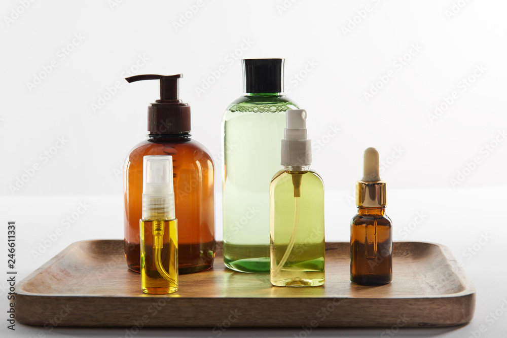 Wooden tray with various cosmetic containers on white background Wooden tray with various cosmetic containers on white background