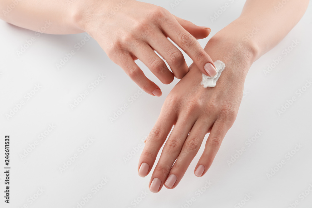 Partial view of woman applying cosmetic cream on hands on white background Partial view of woman applying cosmetic cream on hands on white background