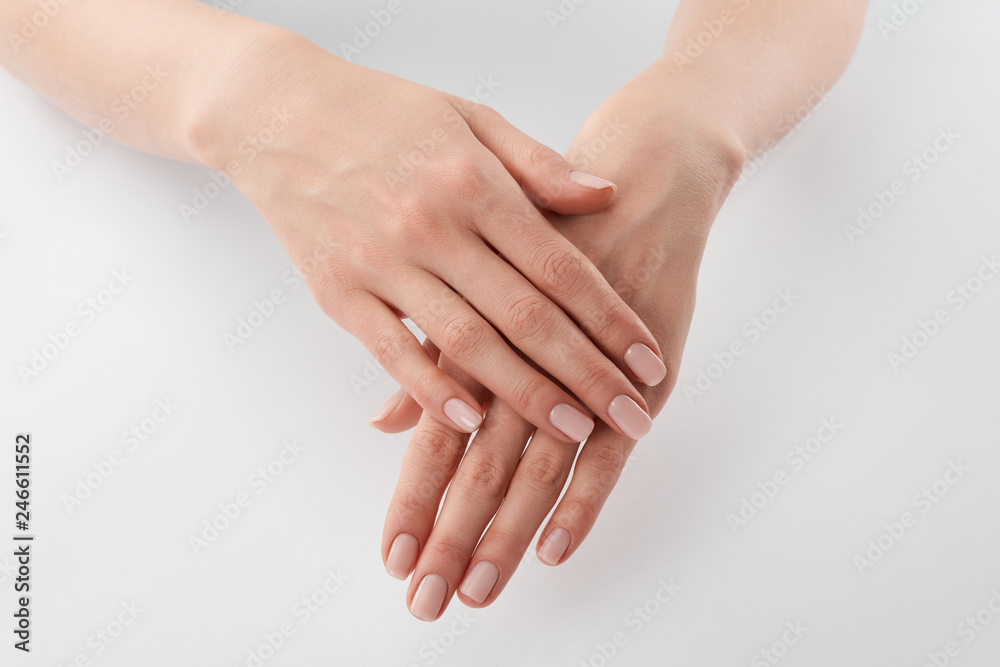 Partial view of female well-cared clanched hands on white background Partial view of female well-cared clanched hands on white background