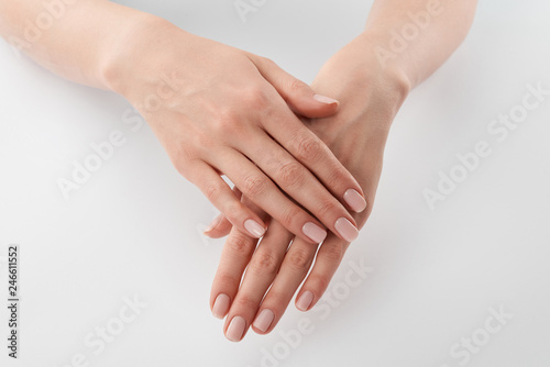 Partial view of female well-cared clanched hands on white background